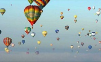 Many hot air balloons floating together